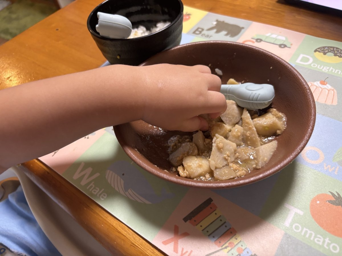 1歳の子どもが自分でスプーンを握り、mogumoの鶏じゃがを食べている手元。具がゴロっと大きめなのがわかる。